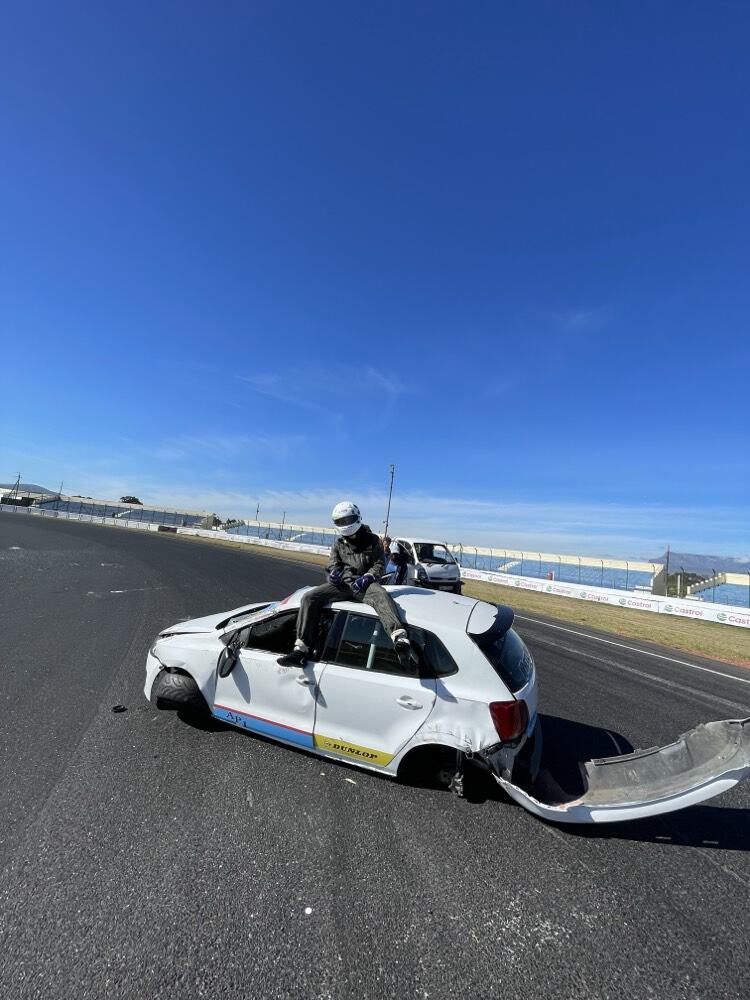 A driver sitting on a race car after a crash